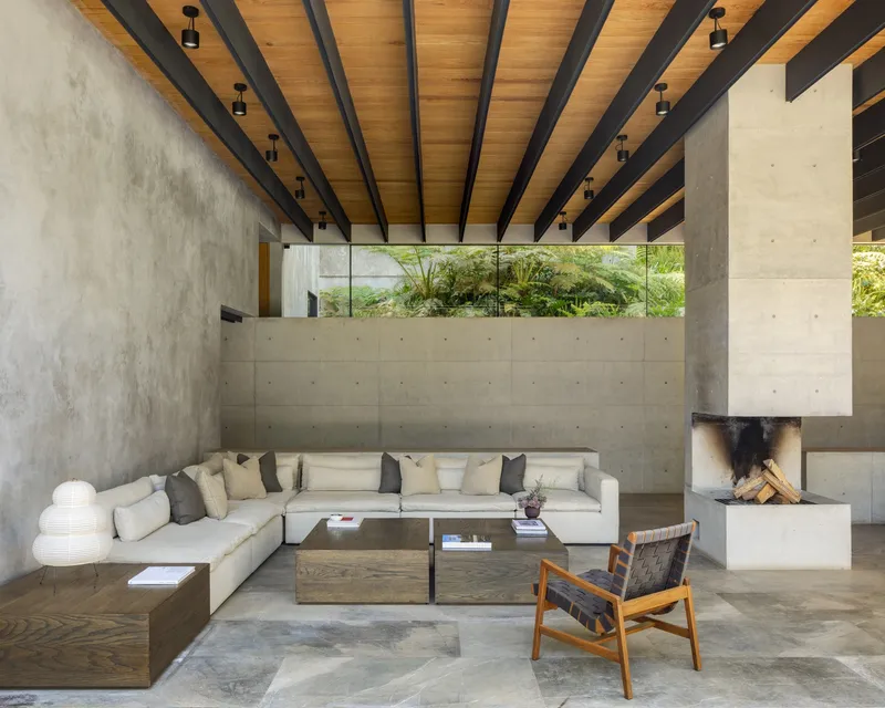 Seating area with sectional sofa and fireplace beneath timber ceiling with exposed black structural beams