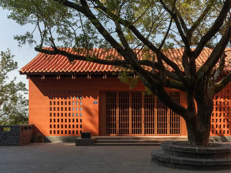Front facade with latticed red tile screen and terracotta roof beneath overhanging tree branches