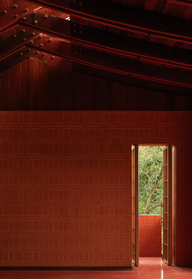 Interior volume with red tile walls and exposed timber roof structure above an open doorway
