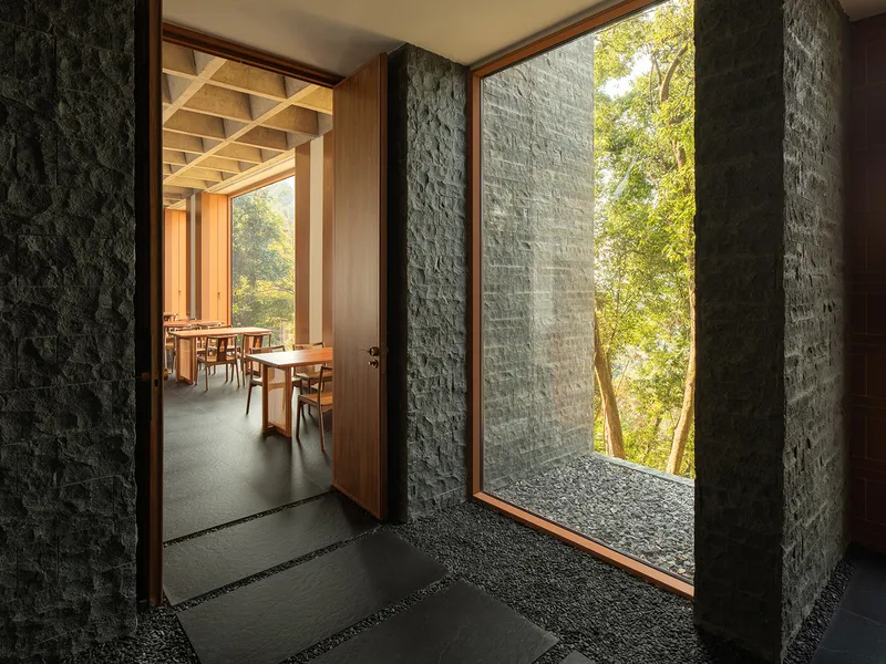 Entry passage with dark stone walls and terrazzo floor opening to dining room at dusk
