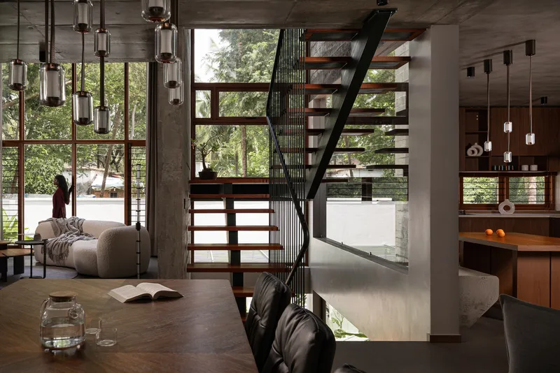 Double-height living space with open timber stair and full-height glazing overlooking garden