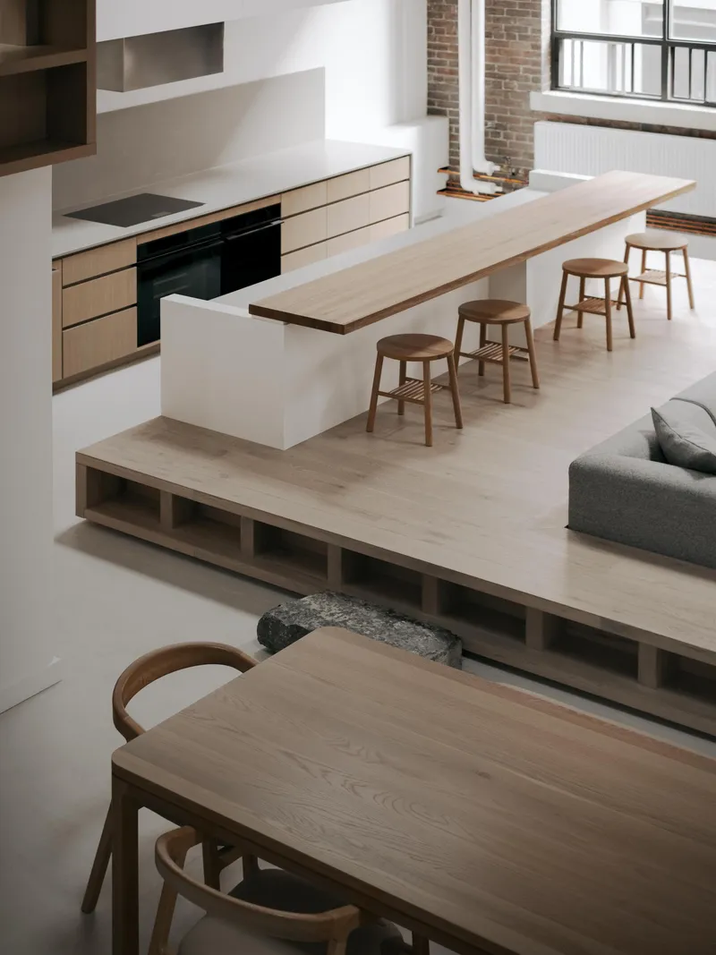 Elevated view of split-level interior showing timber kitchen island with stools and exposed brick column