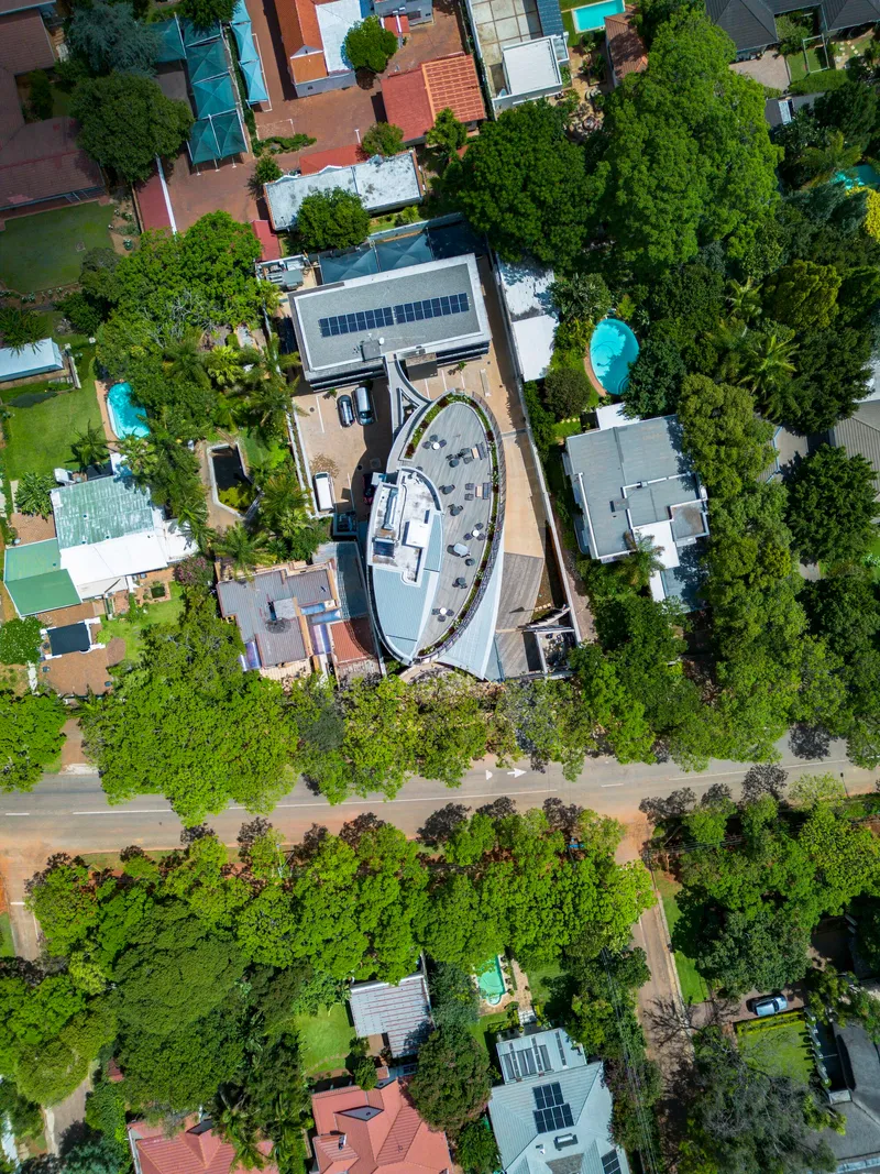 Drone view showing the oval rooftop terrace with solar panels and surrounding tree canopy