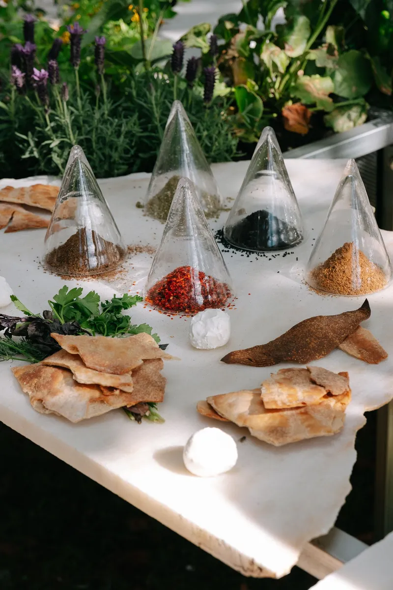 Tabletop display of glass pyramid vessels filled with colored spices and dried herbs