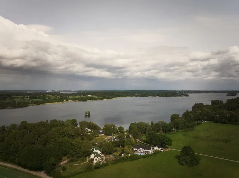 Aerial view of the cluster of barrel-roofed structures nestled among trees beside a lake under storm clouds