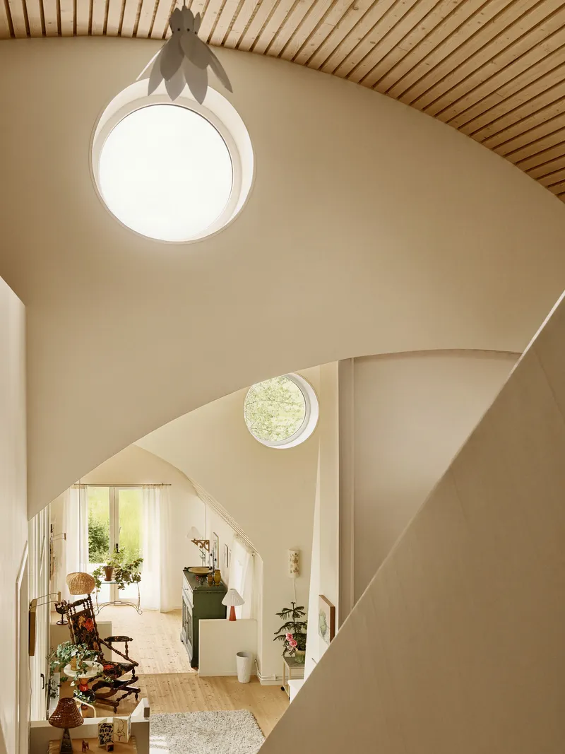 View down through the double-height space showing circular windows and a pendant lamp overhead