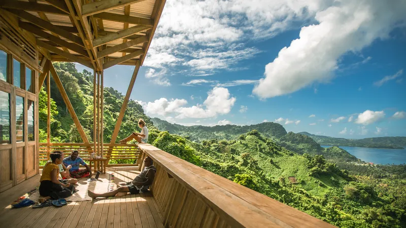 Covered timber deck with visitors seated looking out over forested mountains and distant water