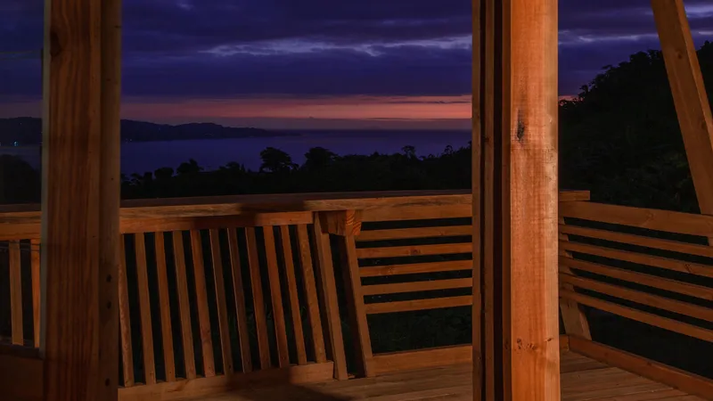 Timber deck with horizontal slatted railing overlooking forested mountains at dusk