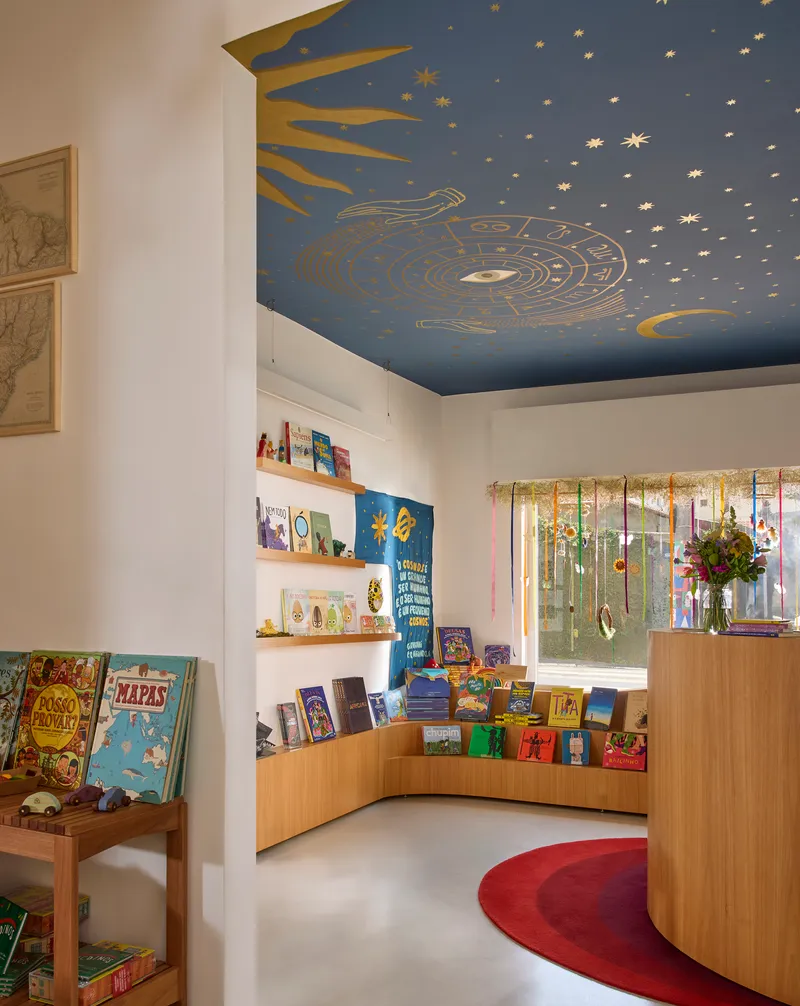 Curved timber display shelving beneath hand-painted celestial ceiling mural with sun, moon, and stars in blue and gold