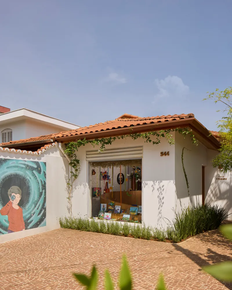 Street facade with clay tile roof, white stucco walls, a painted mural and climbing plants