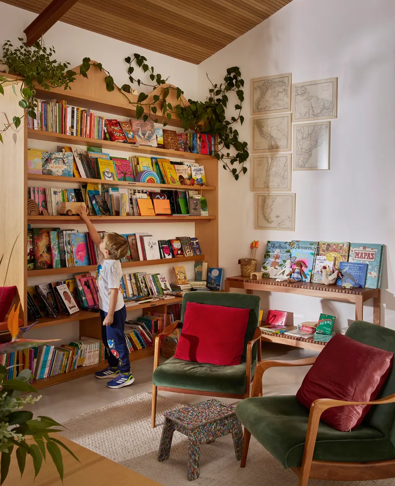 Corner reading nook with timber bookshelves, trailing ivy and a child browsing books