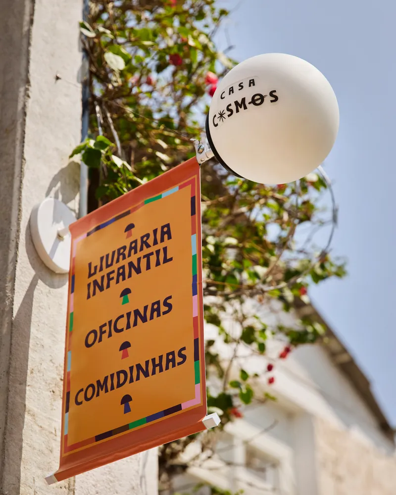 Signage detail showing circular orb light and hanging directory board against leafy trees