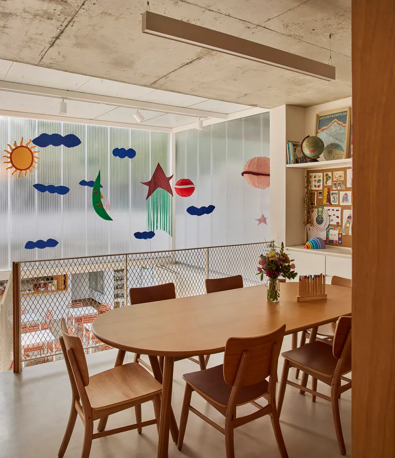 Dining area with exposed concrete ceiling and translucent partition decorated with sun and cloud motifs