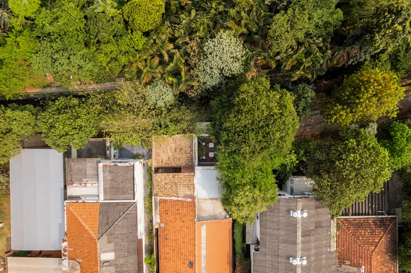 Aerial view of clustered terracotta and corrugated rooftops surrounded by dense tree canopy