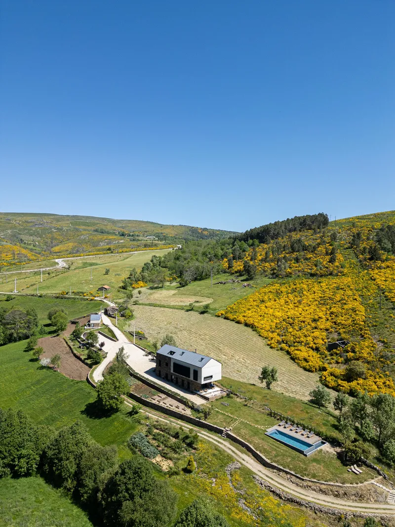 Aerial view of the structure nestled into terraced landscape with pool and vineyards in spring bloom