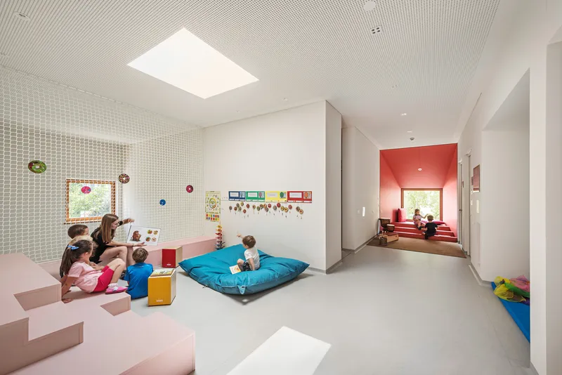 Learning space with perforated wall panel and red alcove window seat visible through open doorway