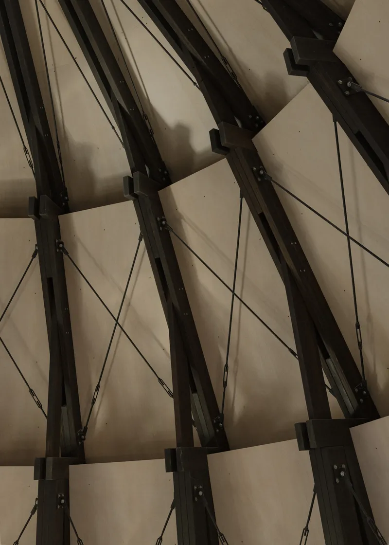 Close-up of the steel beam connections with black metal plates and diagonal cable bracing