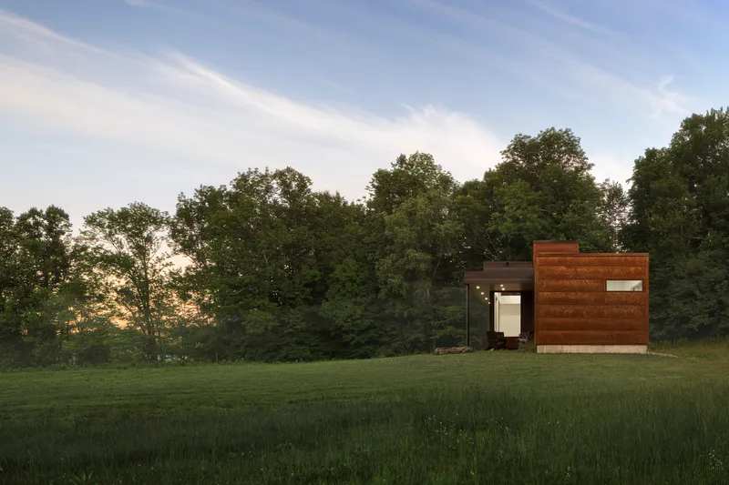 End elevation showing horizontal wood cladding and central glazed opening at sunset