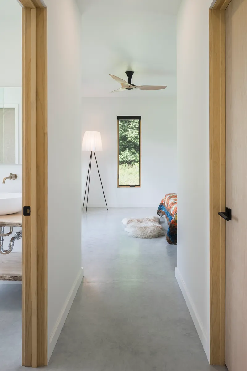 Hallway view with light wood door frames, polished concrete floor, and vertical window