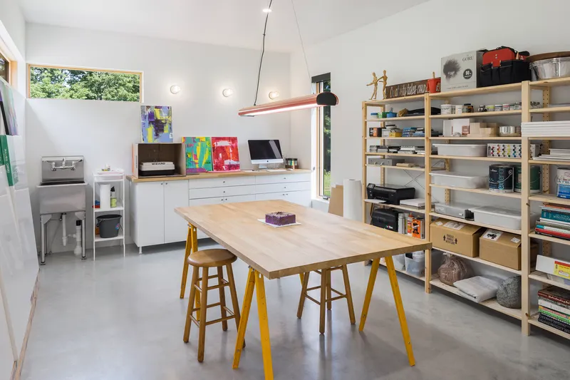 Workshop space with open shelving, work table on yellow trestle legs, and polished concrete floor