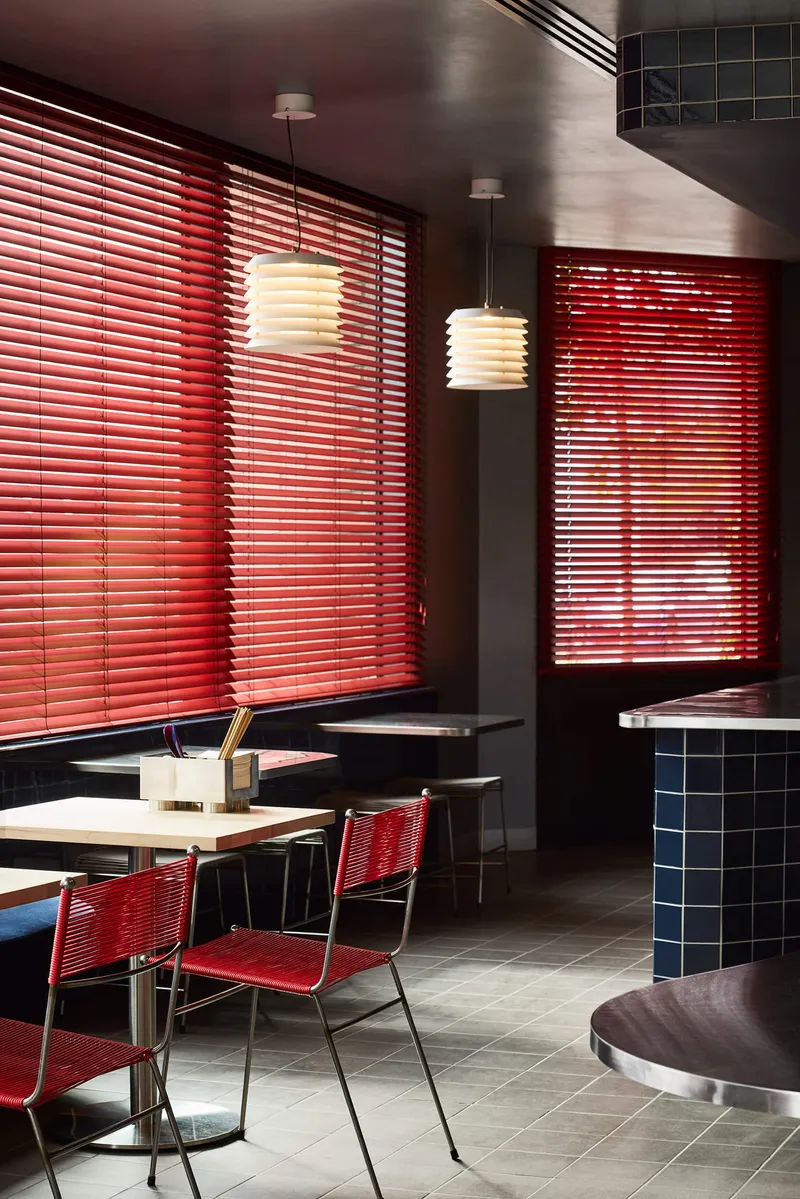 Corner seating booth with red blinds and pendant lights glowing against the dark ceiling