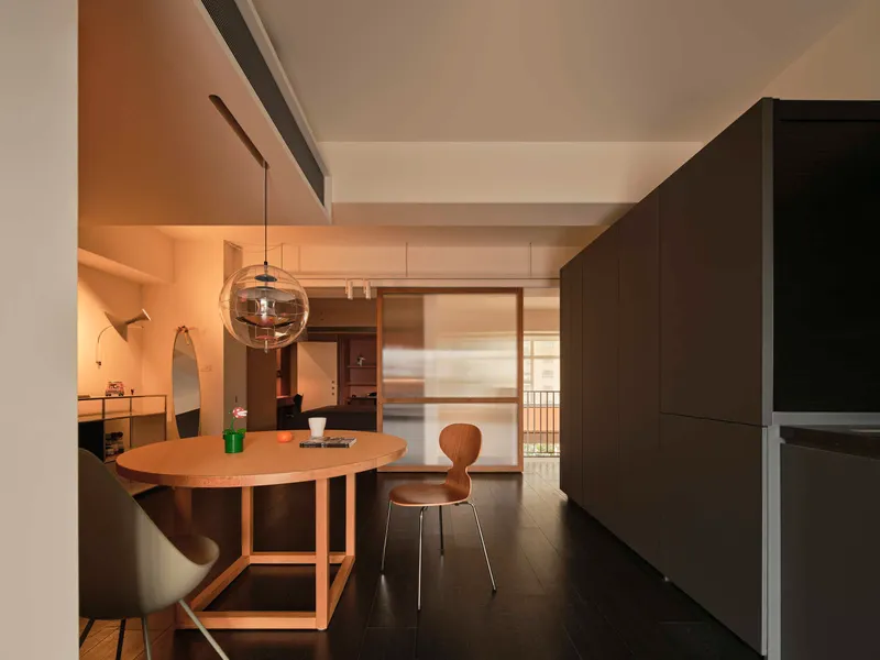 Dining area with timber table and globe pendant light looking through sliding screen toward outdoor balcony