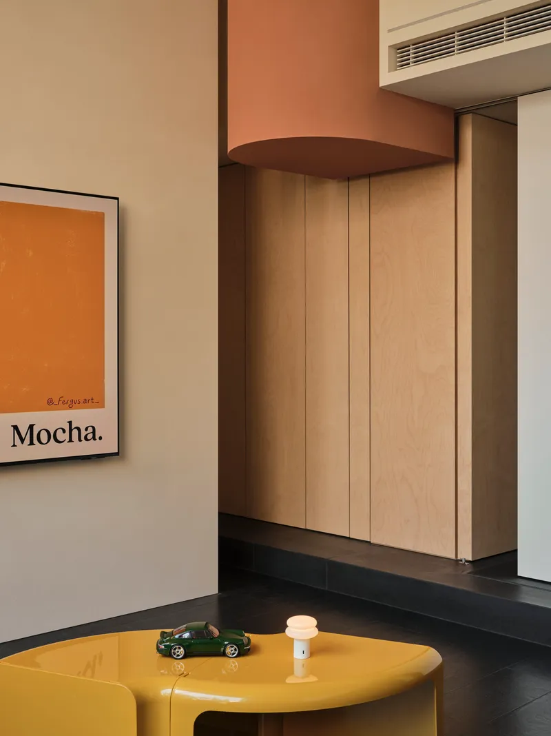 Light wood storage wall with rounded soffit beneath a recessed linear air vent