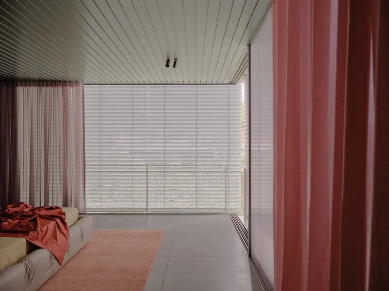 Living room with slatted ceiling, frosted glass privacy screen, and pink curtain panels