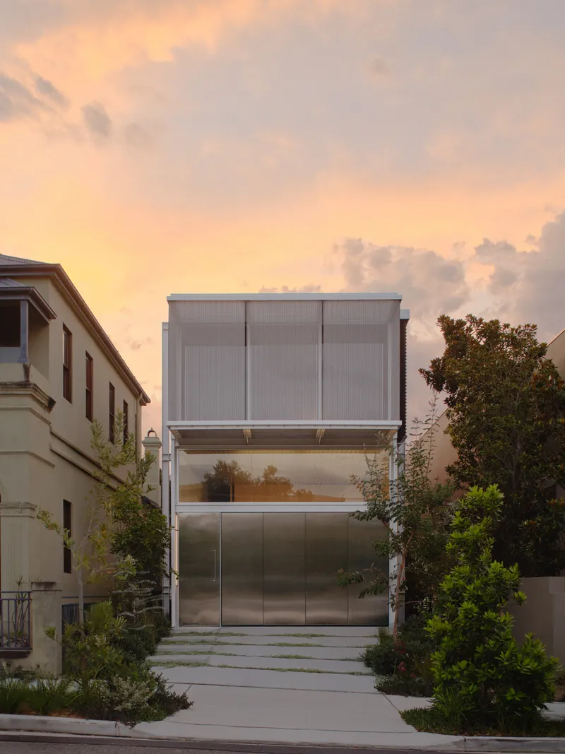 Street view of stacked metal and glass facade with translucent panels at sunset