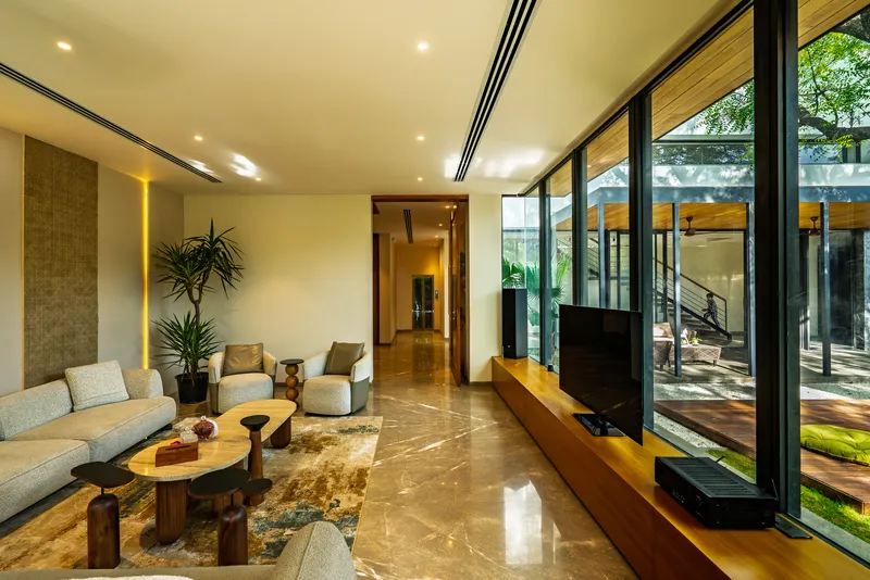 Living room with polished stone flooring and floor-to-ceiling glazing opening to the garden