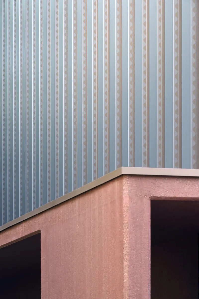 Close-up of pink stucco parapet meeting vertical white metal screen on upper level