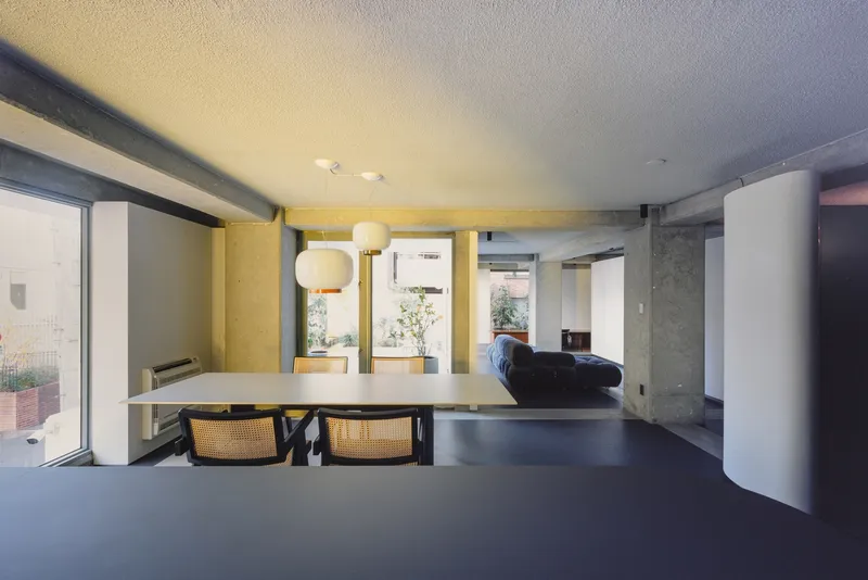 Open living space with exposed concrete beams and white cylindrical column at late afternoon