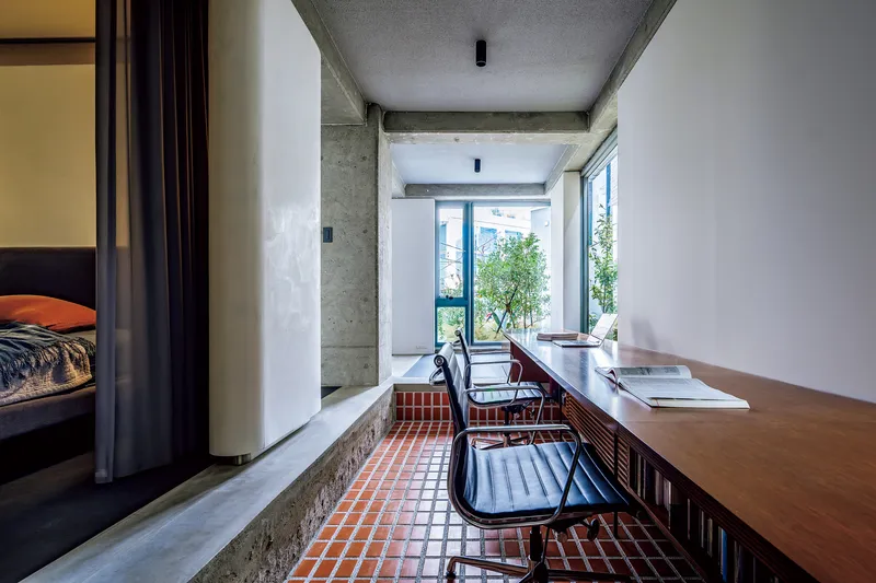 Corridor with red checkered tile floor and timber desk running along white walls toward glazed terrace door