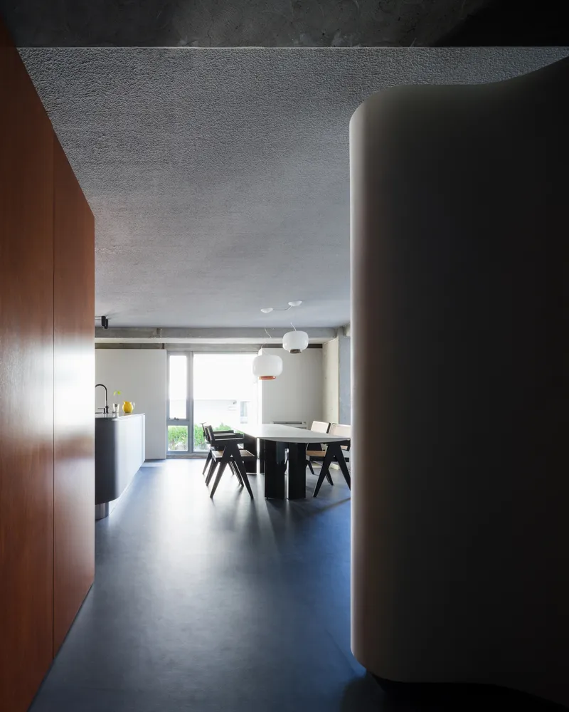 Dining area with timber cabinetry and white cylindrical column beneath a textured concrete ceiling