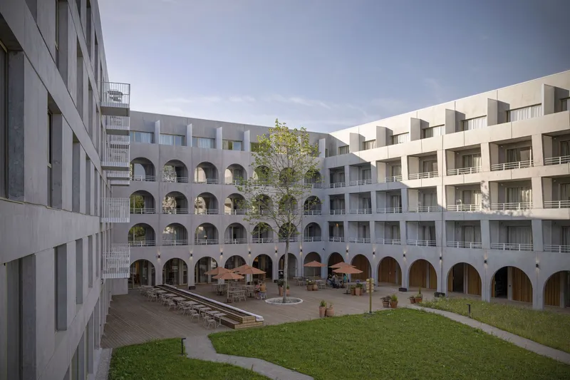 Interior courtyard with arched colonnade surrounding a grassed lawn and scattered outdoor seating