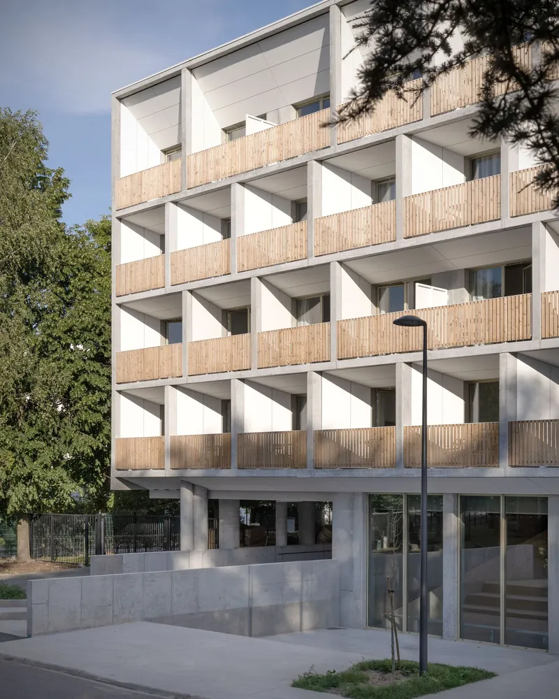 Street facade with timber-screened balconies and triangular white concrete sunshades on each level