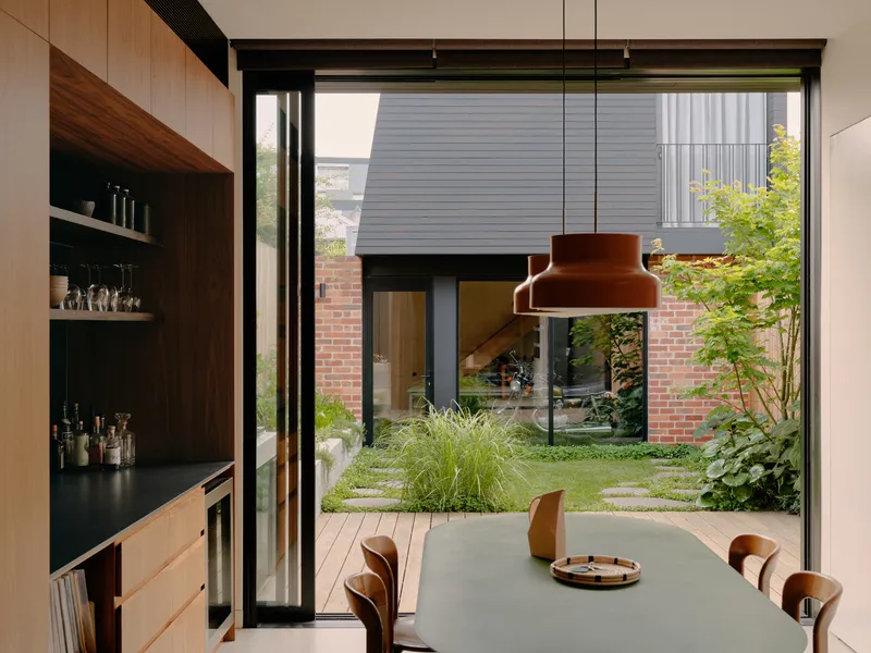 Interior dining area looking through glazed doors to a small planted courtyard