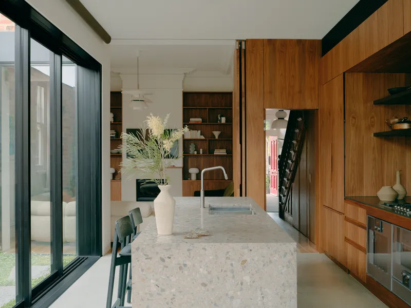 Kitchen island with terrazzo countertop flanked by timber joinery and floor-to-ceiling glazing