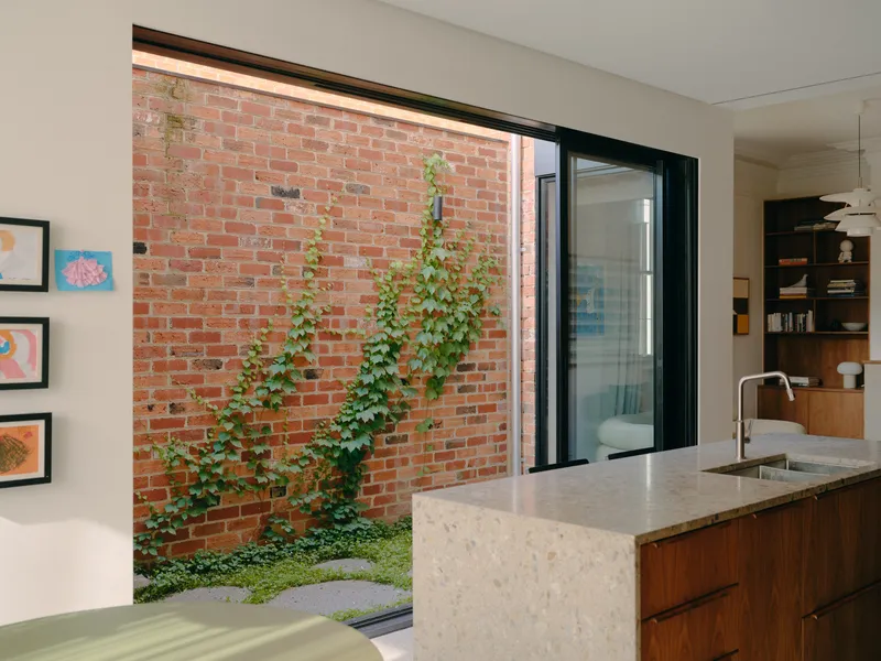 Kitchen island with terrazzo countertop overlooking a small brick-walled courtyard with climbing vines