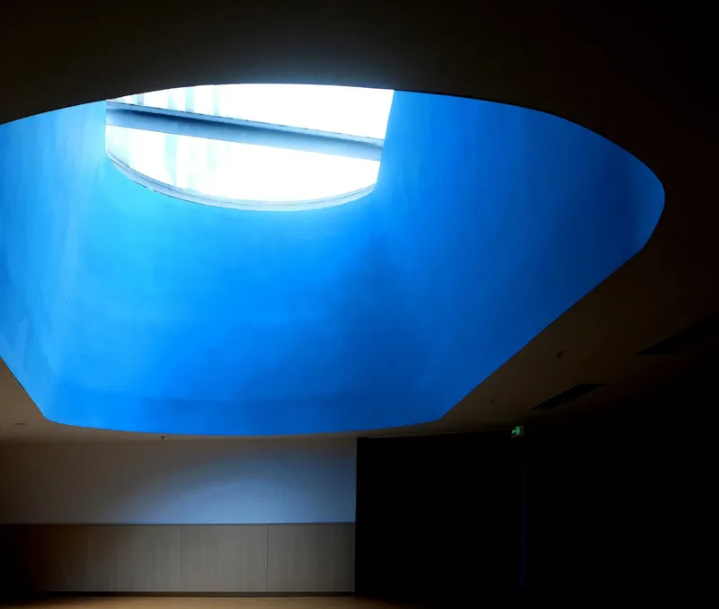 Oval skylight opening with blue sky illuminating the curved interior ceiling from above