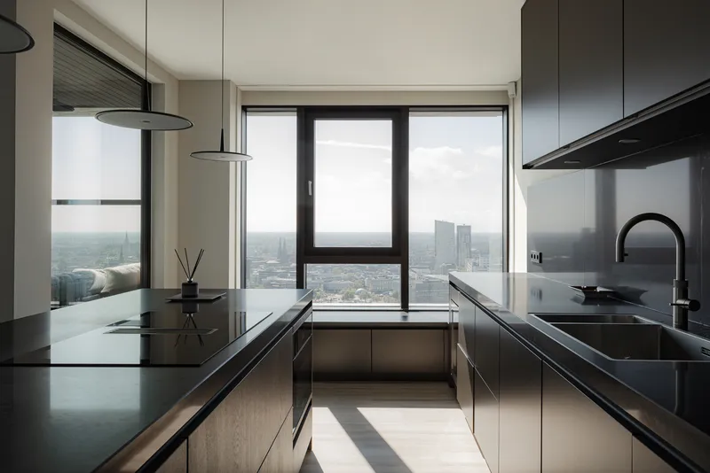 High-rise kitchen with black cabinetry and expansive windows overlooking the hazy cityscape