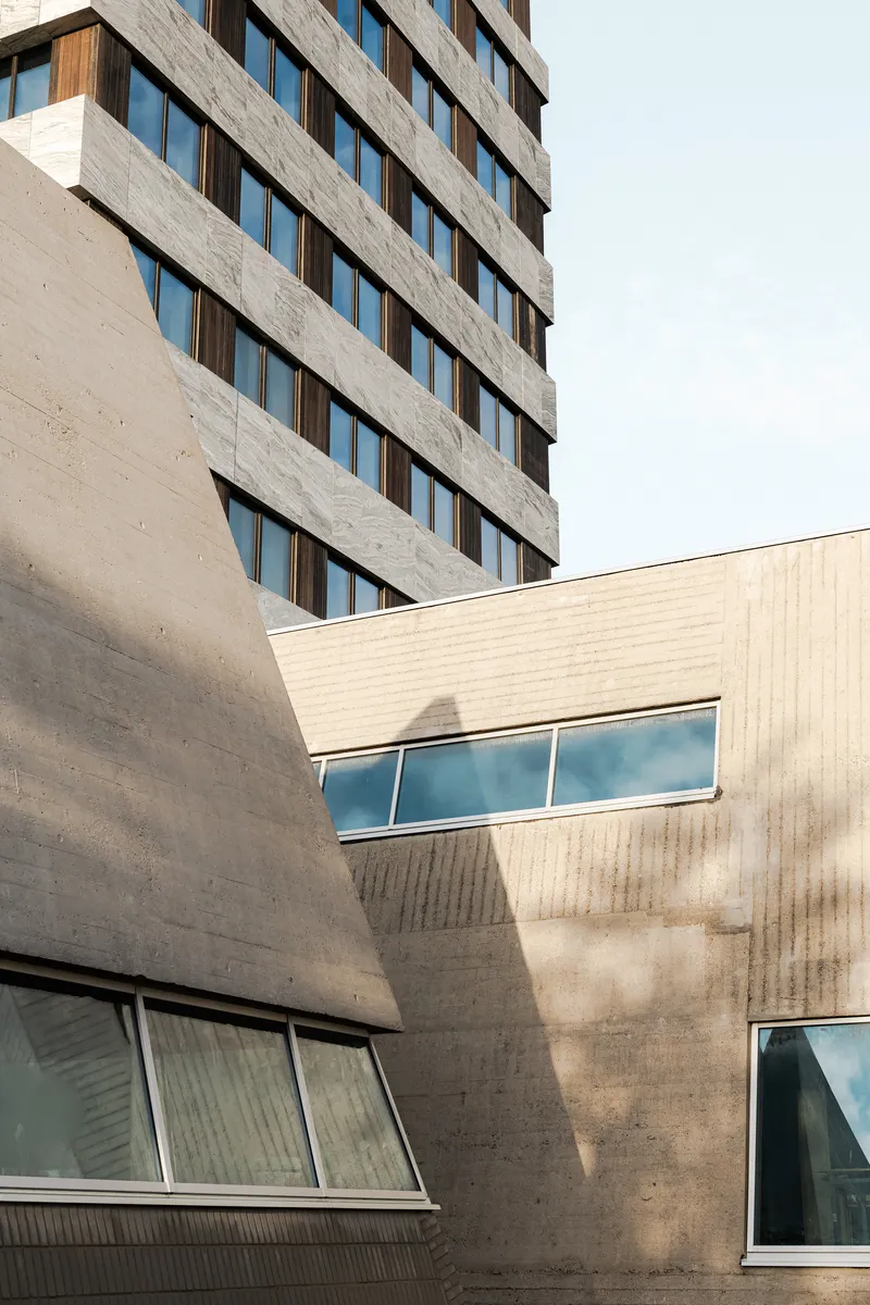 Concrete podium with angled walls and ribbon windows casting shadows in afternoon sun
