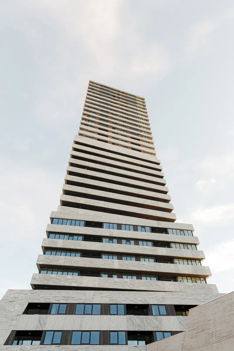 Upward view of the stepped concrete balconies forming a tapering tower against cloudy skies