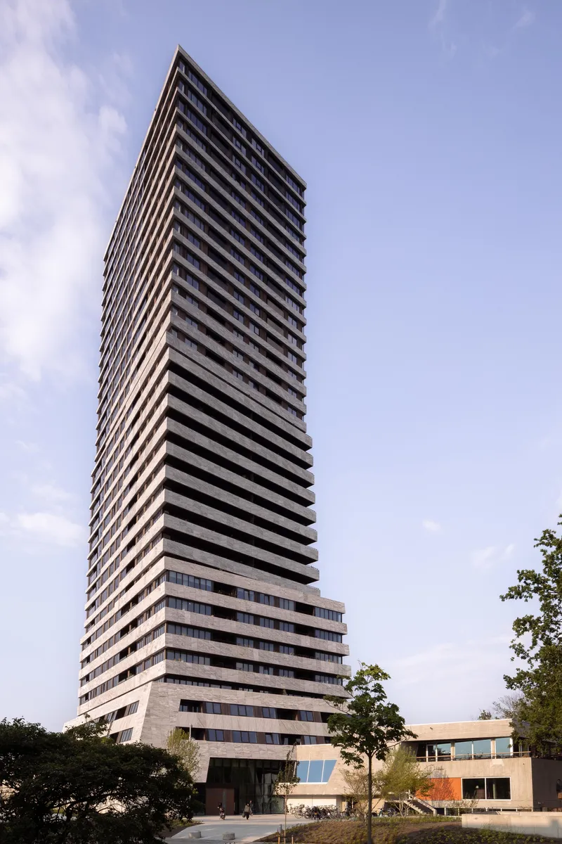 The rotating concrete slabs rising in clear afternoon light with trees at the base