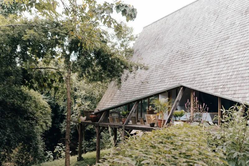 Covered terrace with exposed timber posts and potted plants beneath the sloped tile roof