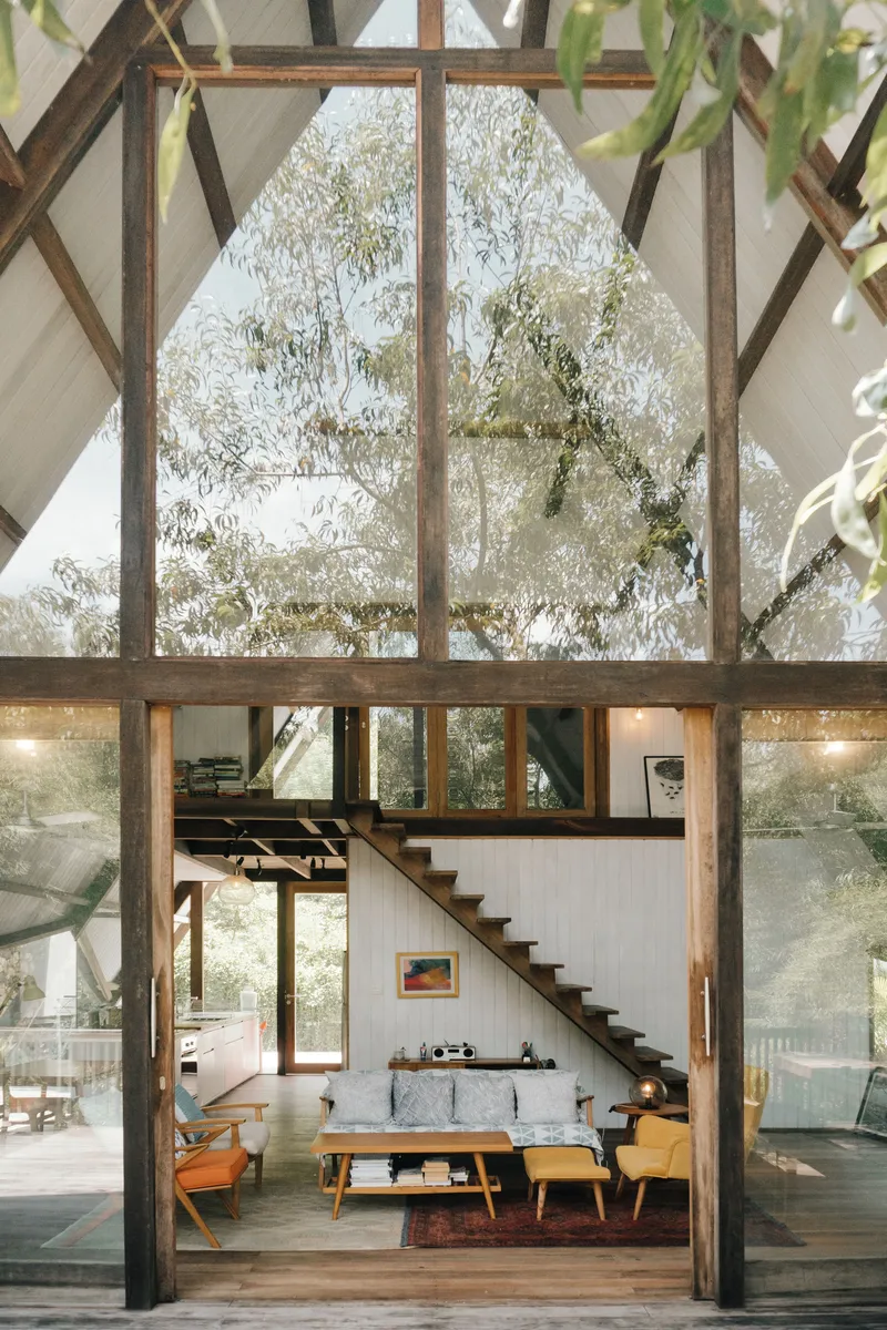 Double-height interior with exposed timber frame, open staircase and frosted gable window
