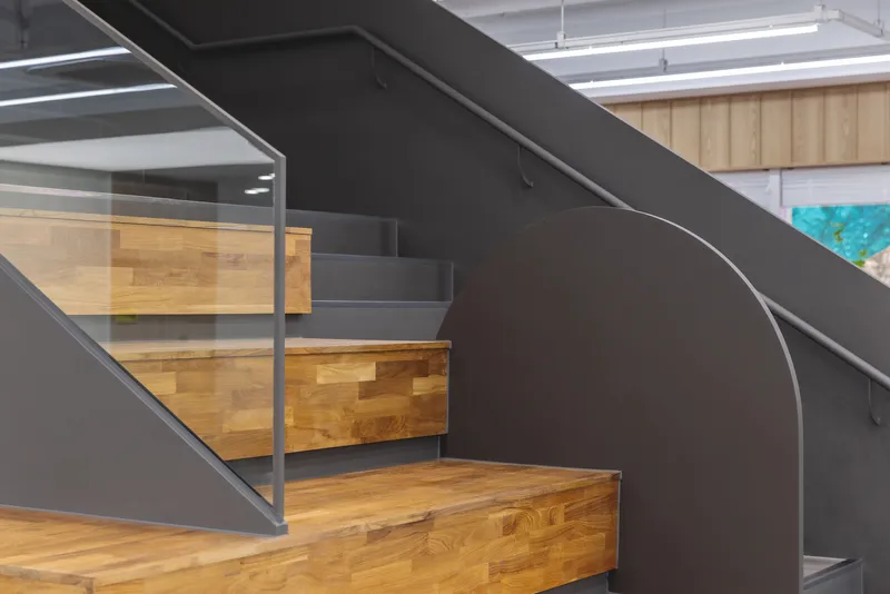 Close-up of the curved staircase with timber treads and black steel stringers and glass railing