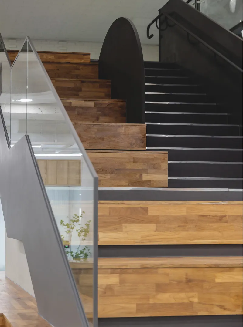 Alternating wood and painted steel treads on the staircase with glass balustrade and potted plant below
