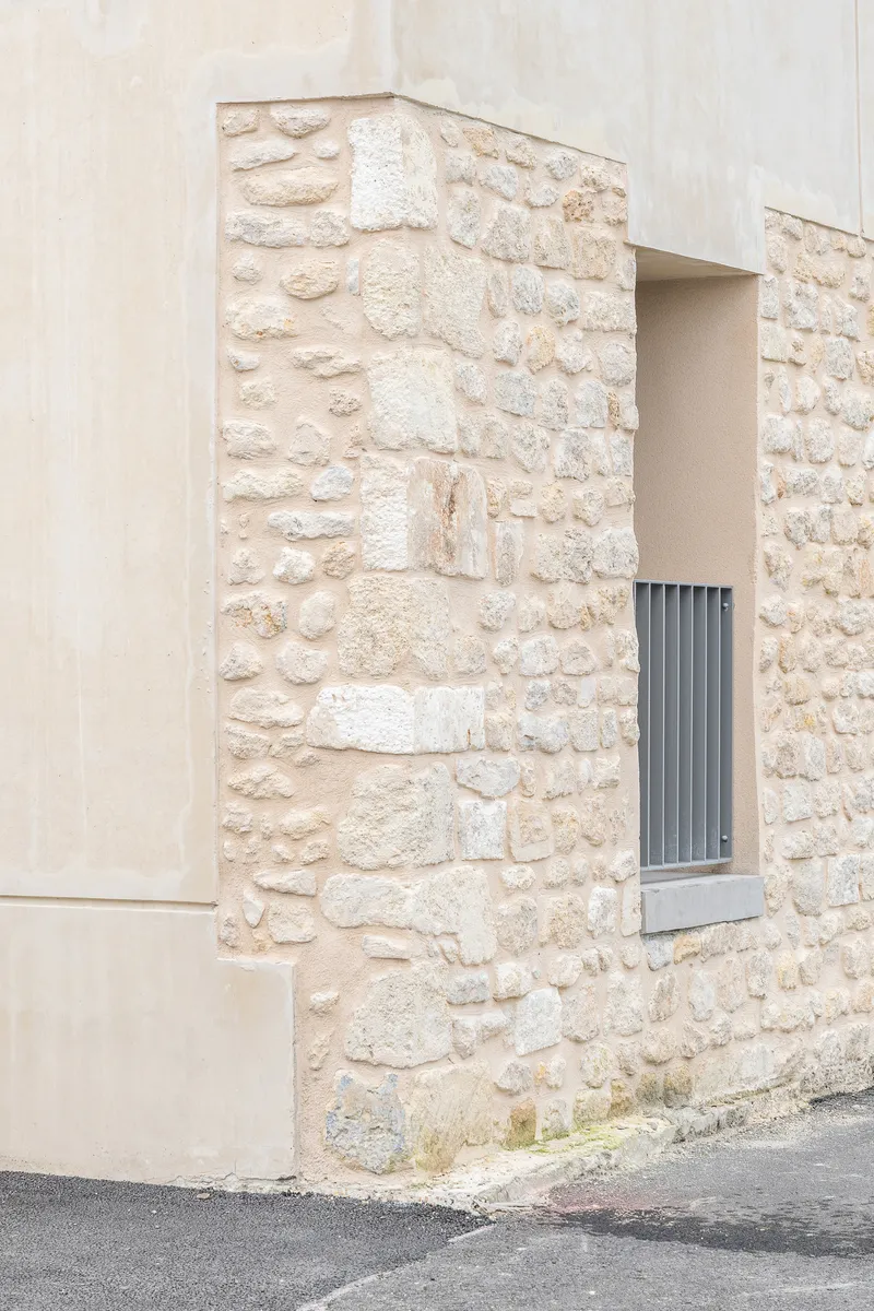 Close-up of the limestone wall corner with a small recessed window and smooth plaster edge