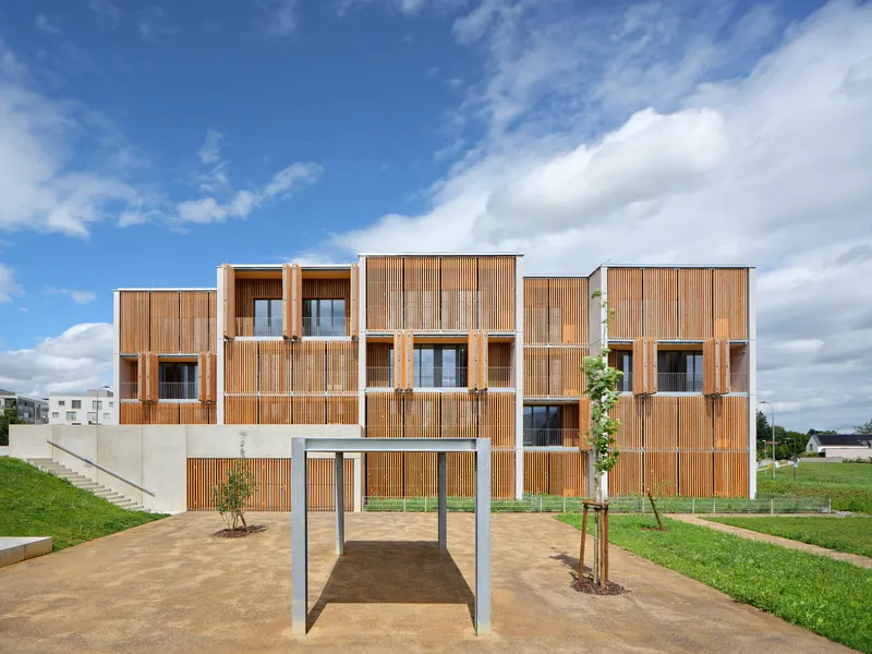 Residential facade showing stacked volumes with vertical timber screening and recessed balconies